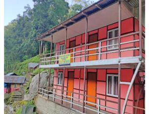 un edificio rojo y naranja al lado de una colina en Rishi River Cottage, West Bengal en Pedong