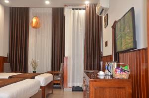 a hotel room with two beds and a desk with a television at Hào Hoa Hotel Kon Tum in Kon Tum +10 photos