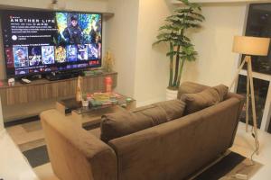 sala de estar con sofá y TV de pantalla plana en A2J Luxury 2BR Suite Near High Street BGC Taguig en Manila