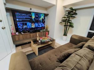 sala de estar con sofá y TV de pantalla plana en A2J Luxury 2BR Suite Near High Street BGC Taguig en Manila