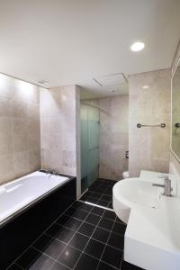 ein Badezimmer mit einer Badewanne, einem Waschbecken und einer Badewanne in der Unterkunft Hanwha Resort Jeju in Jeju-do