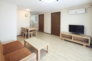 a living room with a couch and a tv and a table at Hanwha Resort Jeju in Jeju