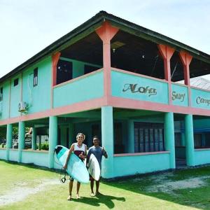 dos personas de pie en frente de un edificio con tablas de surf en Aloha Guest House Nias en Hilibotodane