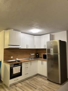 a kitchen with white cabinets and a stainless steel refrigerator at Vila AliBi Valiug - 200m from Ponton Casa Baraj in Văliug