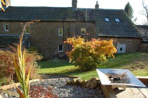a stone house with a garden and a table in front of it at Brigstone Stable - charming peaceful cottage in Lothersdale