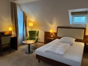 ein Schlafzimmer mit einem Bett, einem Stuhl und einem Schreibtisch in der Unterkunft Boardinghouse am Wall in Salzgitter-Bad