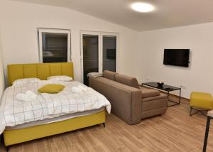 a bedroom with a bed and a couch and a chair at Apartmani TIS in Banja Luka