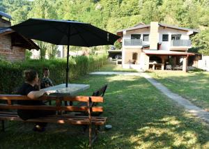 two people sitting on a bench under an umbrella at Apartmani TIS in Banja Luka