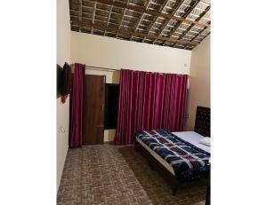a bedroom with a bed and red curtains at Hills Of Adventure, Keshudhar, Lansdowne in Lansdowne