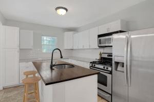 a kitchen with white cabinets and a stainless steel refrigerator at Near Bishop Arts District Spacious 3 Bedroom Home! in Dallas