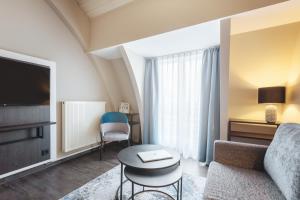 Select Hotel Elmshorn في إلمسهورن: غرفة معيشة مع أريكة وطاولة وتلفزيون