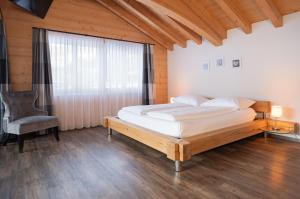 a bedroom with a bed and a chair and a window at Apartment Renata in Grindelwald