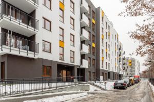 an apartment building on a snowy street with parked cars at Warsaw City North in Warsaw