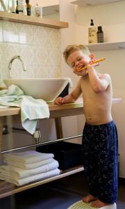 a young boy brushing his teeth in a bathroom at Der Tannenhof in Reutte