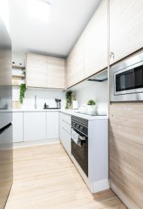 a kitchen with white appliances and wooden cabinets at Nordik Rooms Urban - Centro "Helsinki" in Málaga