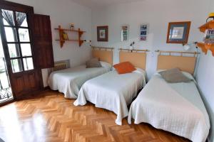 a room with three beds and a wooden floor at Casa Rural El Mirador del Pico in Santa Cruz del Valle