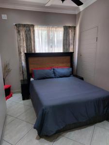 een slaapkamer met een bed met blauwe lakens en een raam bij Villa Pesca Self Catering accommodation in Richards Bay