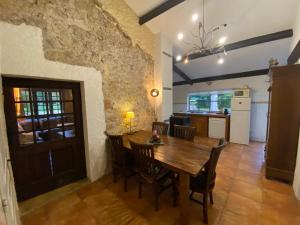 uma cozinha e sala de jantar com uma mesa de madeira e cadeiras em Cosy former bakery house with communal swimming pool em Prayssac