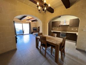 a kitchen and dining room with a wooden table and chairs at T'Anna Farmhouse in Nadur