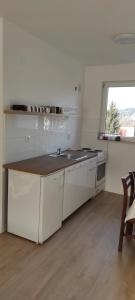 a kitchen with white cabinets and a sink and a window at Apartman MiMa in Pale