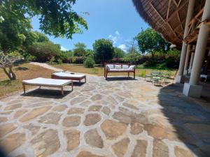 un patio in pietra con due panche sopra di Gulu House a Malindi