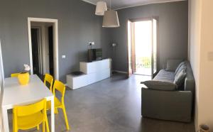 a living room with a couch and a table and yellow chairs at Villa Smeralda in San Vito lo Capo