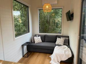 a living room with a couch and two windows at Tiny House Clunes at The Old Butter Factory in Clunes