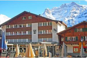 a hotel with chairs and umbrellas in front of a mountain at Appartement au calme avec vue magnifique in Adelboden