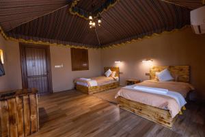 2 łóżka w pokoju z drewnianą podłogą w obiekcie Jebel Shams Resort منتجع جبل شمس w mieście Dār Sawdāʼ