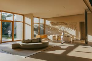 a man walking through a living room with a couch at Six Senses Vana - A Wellness Retreat in Dehradun