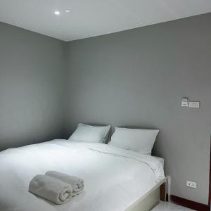 a white bed with two pillows and a towel on it at Aowmana Hotel in Makkasan