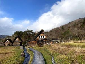 a wooden path in front of houses in a field at WAY SHIRAKAWAGO - Private, Free Parking and Newly Opened 2022 WAY SHIRAKAWAGO in Shirakawa