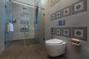a bathroom with a toilet and a glass shower at SaffronStays Mariposa by the River Sol, Karjat in Karjat +11 photos