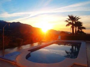 uma piscina com o pôr-do-sol ao fundo em Countryside private apartment with pool & sea view em Torrox