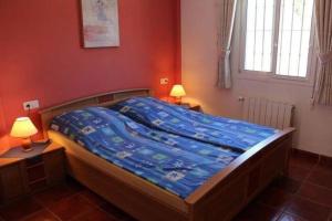 a bedroom with a bed with a blue comforter and two lamps at Countryside private apartment with pool & sea view in Torrox