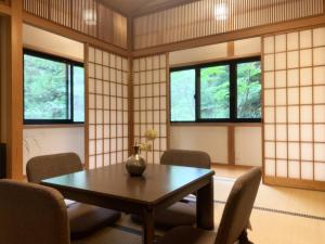 Habitación con mesa, sillas y ventanas. en 一棟貸切 森のお風呂とアウトドアサウナ 日光雪月花 en Nikko