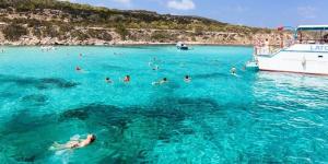 a group of people swimming in the water near a boat at Ascos Coral Beach Hotel in Coral Bay