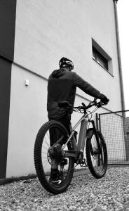 un hombre montando una bicicleta delante de un edificio en B&B Chambre Privative Chez L'habitant Sur La Route Des Vins Parking Box vélo en Issenheim
