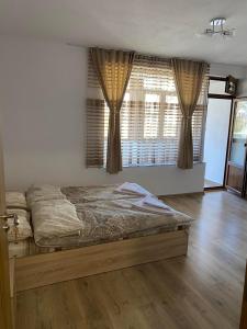 1 dormitorio con 1 cama y una ventana con cortinas en Апартамент за гости en Devin