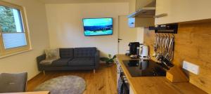 a living room with a couch and a tv on the wall at Apartment auf der Schladminger Sonnenseite - smart, zentral & ruhig in Schladming