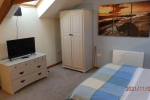 a bedroom with a bed and a tv on a dresser at Spacious 1 bedroom cottage between coasts in North Hill