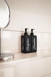 zwei schwarze Flaschen auf einer Theke im Bad in der Unterkunft Pfälzer Herzel in Neustadt an der Weinstraße