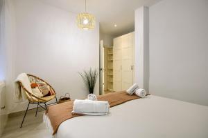 a white bedroom with a bed and a chair at Apartamento Plaza España, Madrid in Madrid