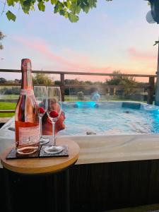 a bottle of wine and glasses on a table next to a swimming pool at The DeerView Lodge in Cardiff