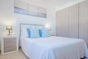 a white bedroom with a large bed with blue pillows at La Barrosa con vistas al mar in Novo Sancti Petri