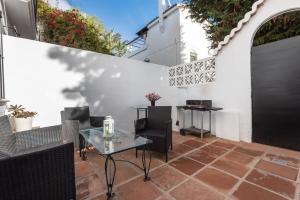 een patio met een tafel en stoelen en een witte muur bij Apartamento Las Cancelas I in Marbella