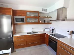 a kitchen with wooden cabinets and a stainless steel refrigerator at Villa Marina Calan Blanes in Cala en Forcat