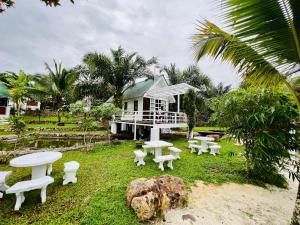 a group of white tables and chairs in front of a house at KASIH SAYANG Farmstay山下人家 in Kluang