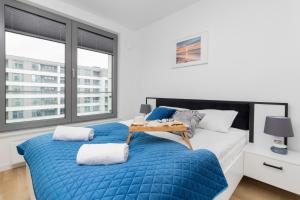 a bedroom with a large bed with a blue blanket at Plac Unii Apartment Gdynia by Renters in Gdynia