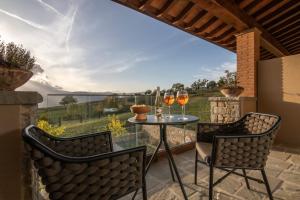 a patio with two chairs and a table with wine glasses at Borgo Corsignano in Poppi